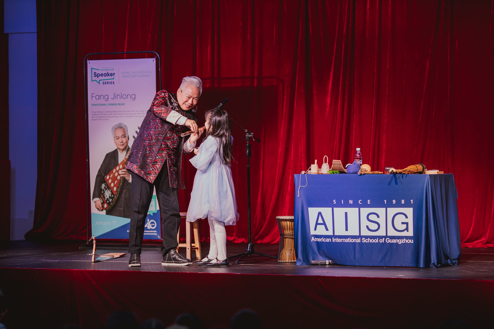 AISG Speaker Series with Fang Jinlong teaches an elementary student with the flute