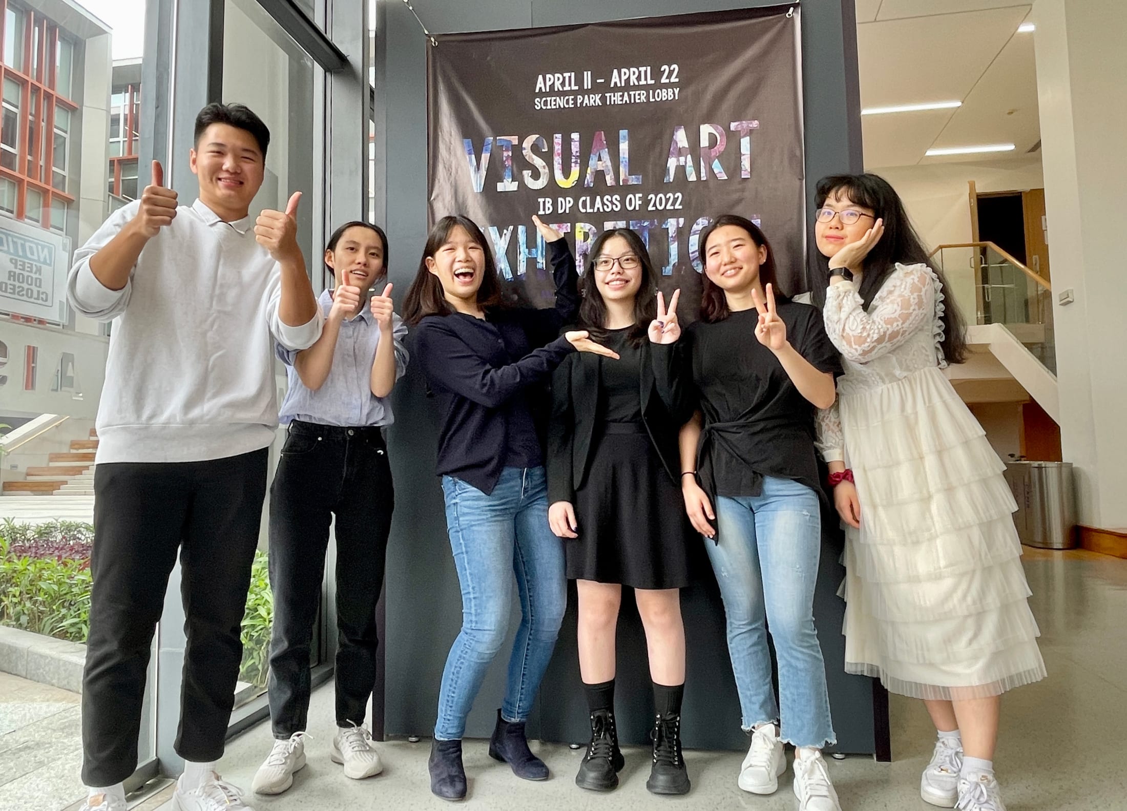 AISG IB Visual Art seniors posing in front of flyer